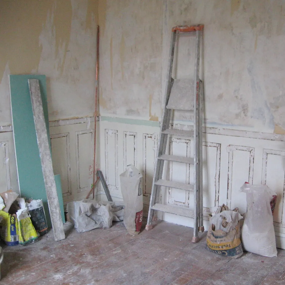 Suivi de travaux d’aménagement intérieur dans une pièce en rénovation avec escabeau et matériaux.